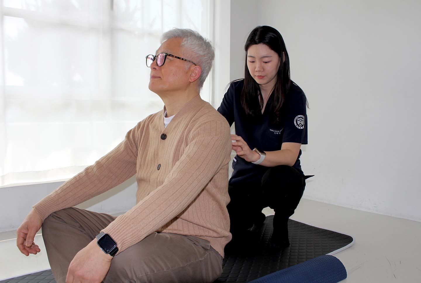 선생님이 앉아 있는 어르신의 자세와 등 근육을 확인하는 첫 평가 장면